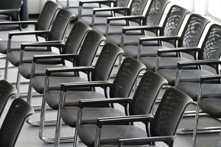 Black and white image of neat rows of conference chairs. The rows are empty, anticipating a group of at least 30 attendees.